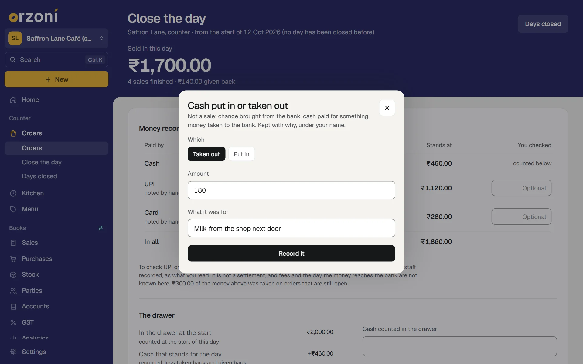 The sheet Cash put in or taken out, over Close the day for the made-up Saffron Lane Café (sample). Its first lines say it is not a sale: change brought from the bank, cash paid for something, money taken to the bank, kept with why, under your name. Under Which, Taken out is chosen and Put in is beside it. Amount is 180, What it was for is Milk from the shop next door, above the button Record it.